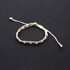 Ethnic woven rope bracelet with lavender beads and vintage metal charms on grey base