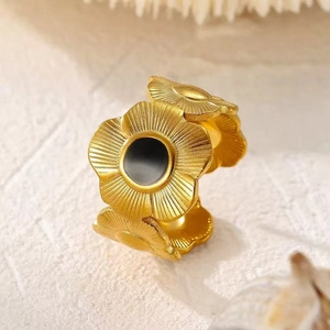Macro detail of adjustable gold flower ring with matte finish and black center inlay