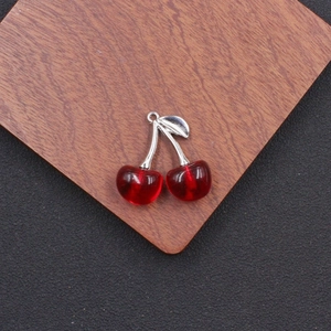 Detailed view of red acrylic double cherry pendants with silver metal stems for DIY jewelry