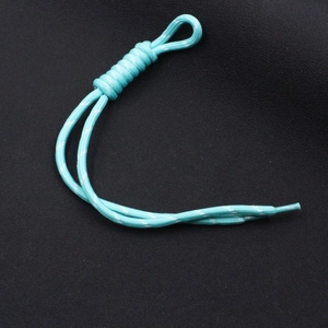 Detail of cyan woven nylon zipper pull with white reflective dots and heat-shrink end cap