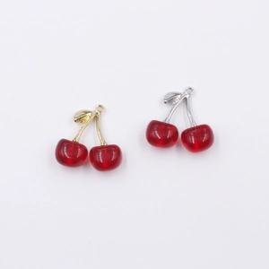 Detail of red translucent cherry charms with gold and silver leaf-shaped metal loops
