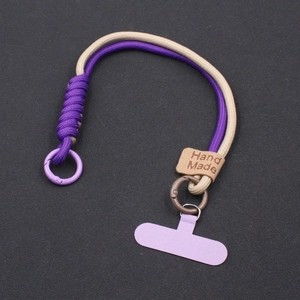 Detailed close-up of handmade purple and beige woven wrist strap with metal ring connector