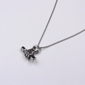 Close-up of silver stainless steel pendant with fist holding dumbbell on a box chain