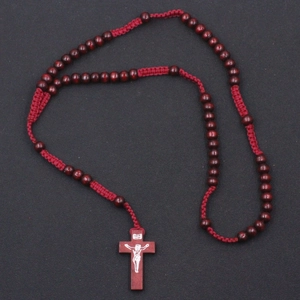 Detailed close-up of 8mm red wood prayer beads and cross pendant on black background
