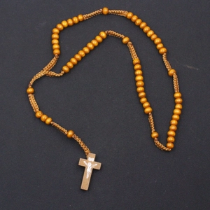 Macro view of 8mm brown wooden prayer beads with detailed crucifix pendant on woven cord