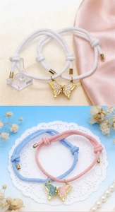 Detalle de pulseras de pareja tejidas a mano con dije de mariposa magnética y corazón