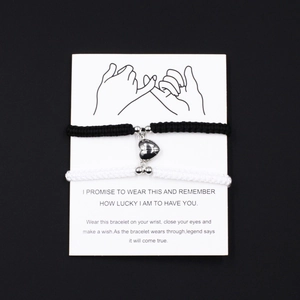 Detail of magnetic heart charms on black and white woven couple bracelets with pinky swear card