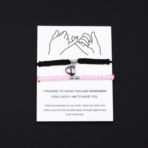 Handmade woven couple magnetic bracelets in black and pink with heart magnet on card