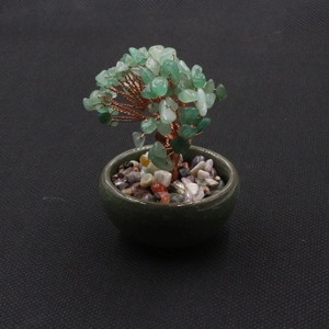 Macro view of green gemstone money tree with copper wire and dark ceramic base