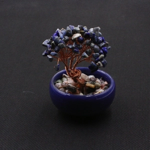 Detail of handcrafted blue crystal tree with copper wire branches in ceramic pot
