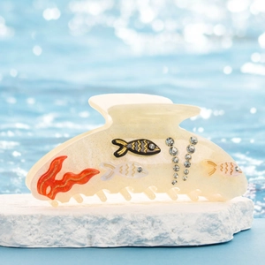 Détail de la pince à cheveux nautique avec strass et motif de poisson sur eau
