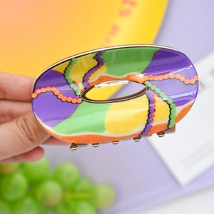 Macro detail of high-gloss acetate hair claw clip with colorful abstract wave patterns