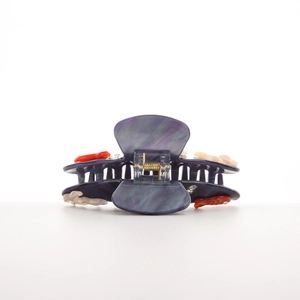 Détail d'une pince à cheveux en résine marbrée violette avec petits ornements colorés