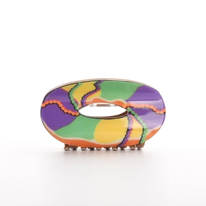Detail view of oval hollow hair claw clip with colorful vintage wave patterns