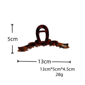 Detail view of tortoiseshell bow hair claw clip showing 13cm size and resin texture