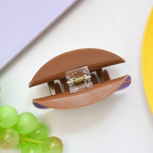 Detail view of large brown hair claw clip with purple wave patterns and metal spring