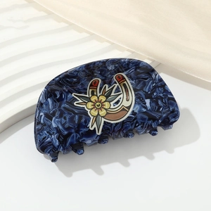 Detail of dark blue marble acetate hair claw with horseshoe and floral illustration