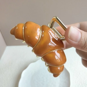 Detailansicht der glänzenden Croissant-Haarklammer mit goldenem Metall-Federmechanismus