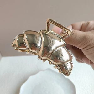 Makroaufnahme der großen goldenen Haarklammer im Croissant-Design aus Metall