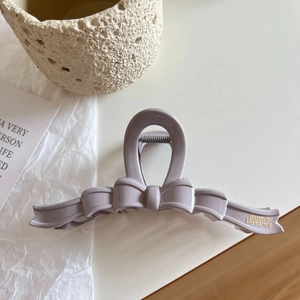Detailed close-up of a lavender bow hair claw clip with golden Barrette La France branding