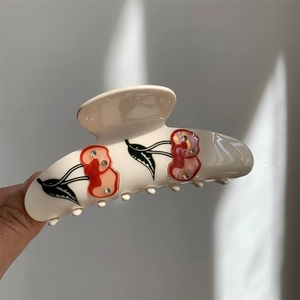 Detailed view of luxury rhinestone cherry hair claw clip in creamy white finish