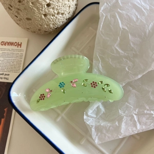 Close-up of translucent green hair claw clip with colorful rhinestone floral pattern