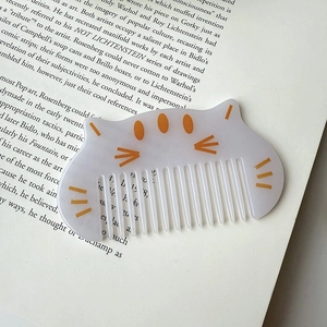 Close-up of a translucent purple cat-shaped hair comb on an open art book