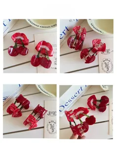 Detailed views of red cherry hair claw clip with green leaf and translucent resin finish