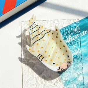 Macro view of whale shark shaped acetate hair claw clip with yellow dots and pearly finish