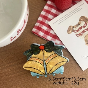 Détail de la pince à cheveux cloche de Noël avec finition acétate et nœud en ruban vert