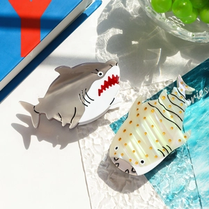 Detail view of acetate hair claws in shark and whale designs with pearlescent finish
