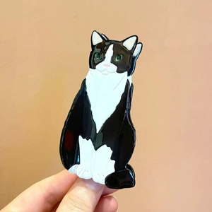 Close-up of a cute tuxedo cat hair claw clip made of glossy acetate with green eyes