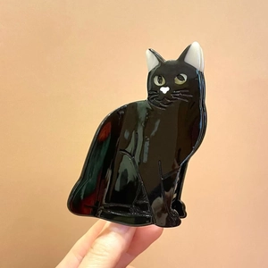 Detailed view of the sleek black cat-shaped hair claw clip with glossy finish