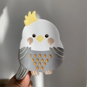 Detail of bird-shaped acetate hair claw clip with golden glitter and cute parrot design