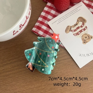 Détail d'une pince à cheveux sapin de Noël verte avec pois colorés et étoile rouge
