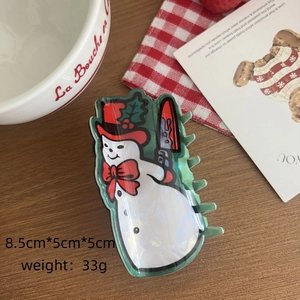 Détail d'une pince à cheveux bonhomme de neige avec chapeau rouge et motif couteau