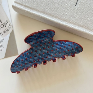 Detailed view of denim texture hair claw clip with red polka dots and red inner teeth