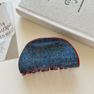 Detail of denim texture hair claw with red polka dots and reinforced red piping edges