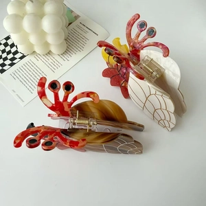 Détail de pinces à cheveux en acétate en forme de coquillage avec motifs rouges