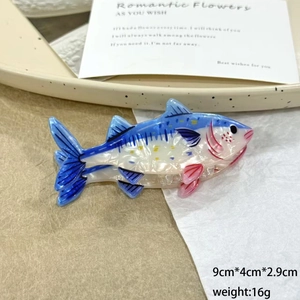 Detail view of fish-shaped hair claw clip with blue marble texture and 9cm dimensions