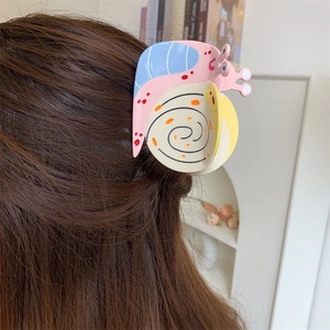 Colorful snail-shaped acetate hair claw clip with patchwork design on long brown hair