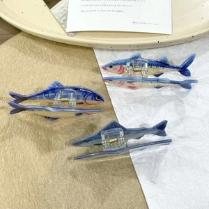 Creative blue fish-shaped hair claw clips with gradient texture on ceramic tray