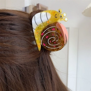 Detail view of the colorful snail shaped acetate hair claw clip worn on long brown hair
