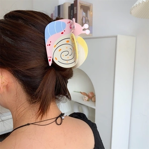 Detail of a large snail-shaped acetate hair claw with pink and blue color-blocking on hair