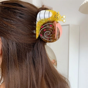 Detail showing colorful snail-shaped acetate hair claw clip worn on long brown hair