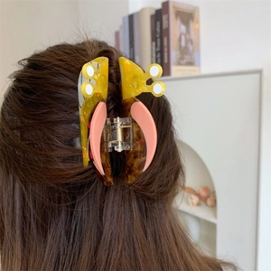 Detail of snail shaped acetate hair claw clip with colorful patterns worn on hair