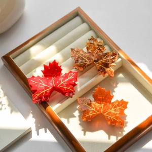 Elegant maple leaf hair claws in three colors with rhinestones on a velvet tray
