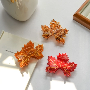 Detail of maple leaf hair claw clips featuring gold veins and sparkling rhinestone accents