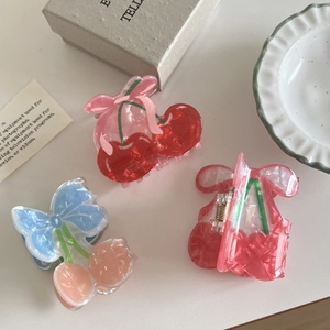 Chic cherry-shaped hair claw clips with elegant bow details on a soft cream background