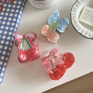 Three pearlescent cherry-shaped acetate hair claws in red, pink, and blue colors